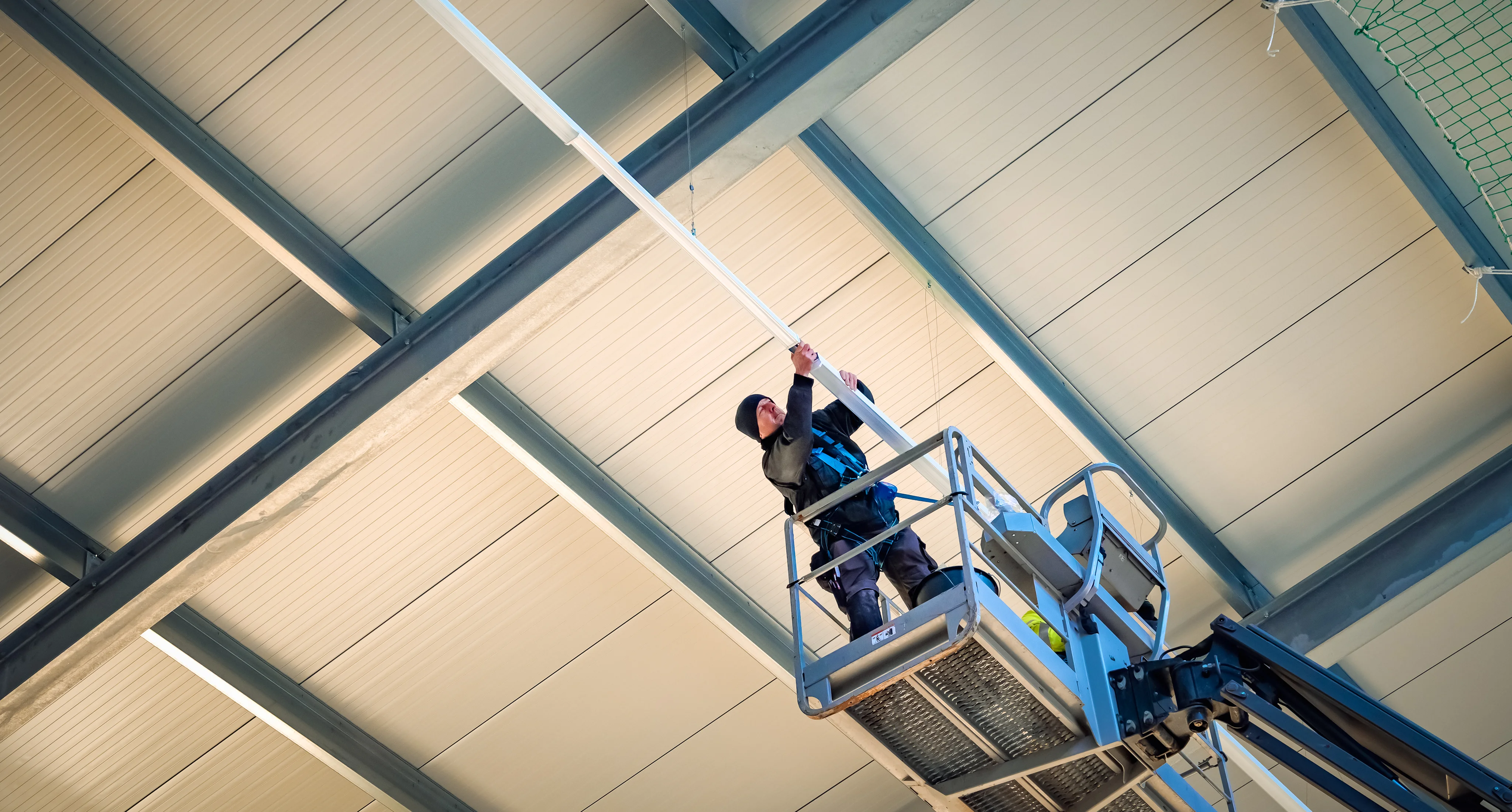 Ein Mitarbeiter der Firma Holthaus bei der Montage von Deckenleuchten