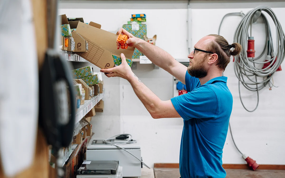 Ein Mitarbeiter an einem Regal mit verschiedenen Bauteilen